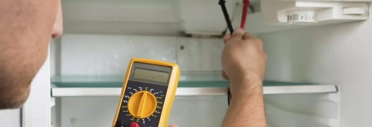 Refrigerator repair technician testing electrical components with a multimeter in Hialeah, FL