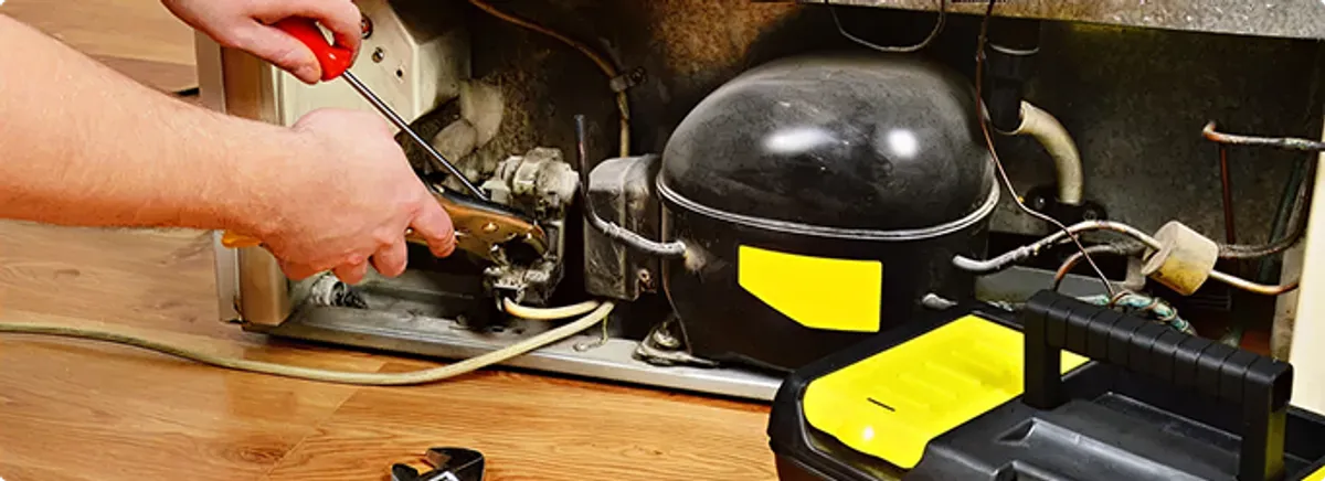 Refrigerator repair technician fixing the compressor and wiring in Hialeah, FL